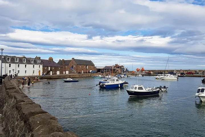 Boats moored in a quiet harbor surrounded by traditional stone buildings
