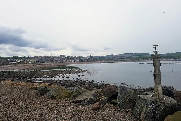 Coastal landscape with rocky shore, sandy beach, and town in the distance